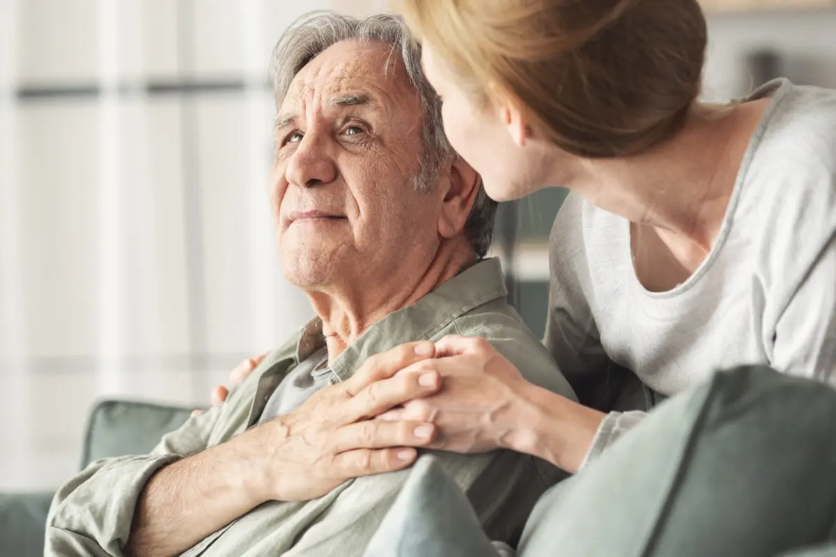 sundowning-family-support-the-village-senior-living-tacoma Adult daughter comforting her senior father at home in the late afternoon showing symptoms of sundowning